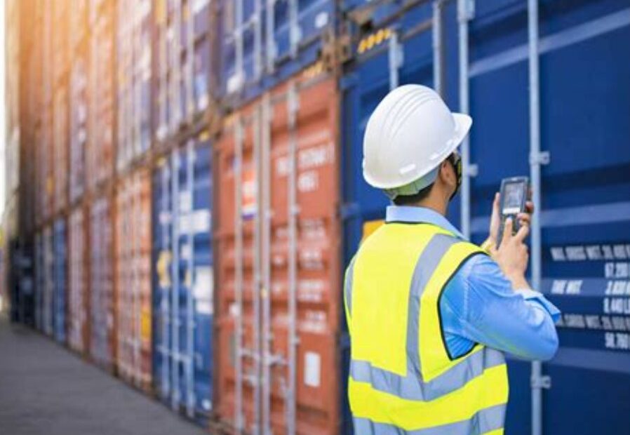 Inspector de mercancías revisando contenedores marítimos en puerto con dispositivo digital